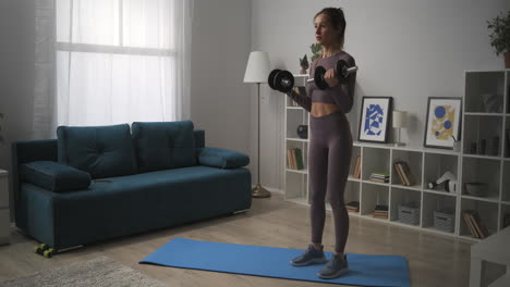 young-woman-with-ponytail-is-lifting-dumbbells-in-living-room-training-at-home-fitness-and-wellness-healthy-lifestyle-moving-panoramic-shot